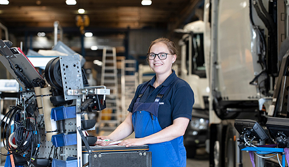 Foto einer Frau in Arbeitskleidung, die in einer Werkstatt arbeitet.