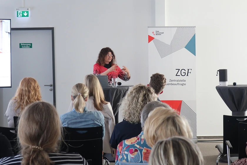 Dr. Maya Götz an steht an einem Stehtisch, im Hintergrund ein Aufsteller der ZGF