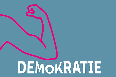 Ein muskulöser Arm, der den Schriftzug Demokratie eindrückt