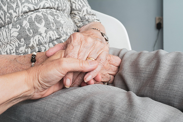 Eine junge Frauenhand hält eine ältere Frauenhand